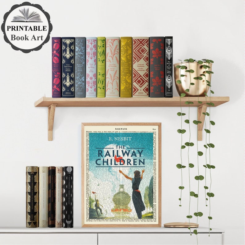 Puede incluir: Una impresi&oacute;n de arte de libro imprimible con una ilustraci&oacute;n vintage de una ni&ntilde;a saludando desde un tren con el texto "The Railway Children" y "E. Nesbit" sobre un fondo azul. La impresi&oacute;n est&aacute; rodeada por un borde blanco y se muestra en un estante con una fila de libros coloridos y una planta en maceta.