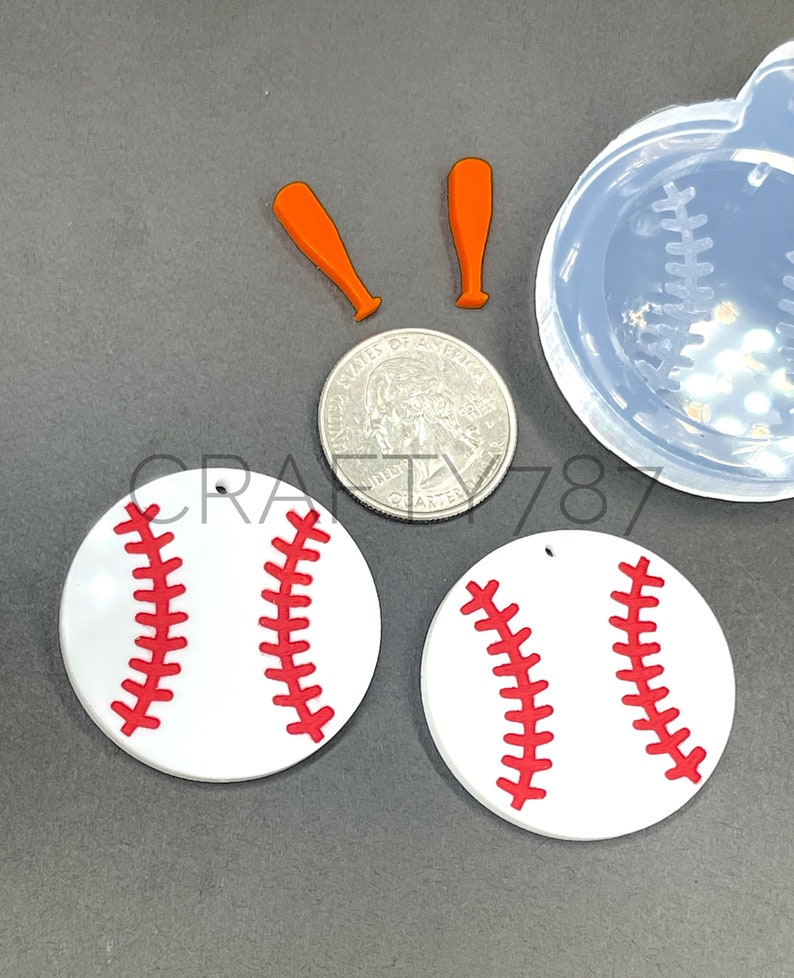 May include: Two white baseball-shaped resin earrings with red stitching. The earrings are shown next to a quarter and two orange baseball bats.