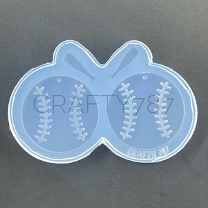 May include: Clear silicone mold with two baseball shapes and two bats. The mold is designed to create resin earrings or charms.