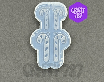 May include: Clear silicone mold with two candy cane designs. The mold is shaped like a rectangle with rounded corners.