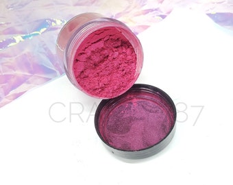 May include: A small jar of pink mica powder with a black lid. The powder is a fine, shimmery texture.