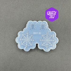 May include: Clear silicone mold for making resin earrings. The mold features two spider web designs and two spiders.