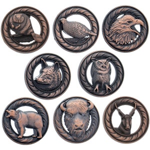 May include: Set of eight copper-toned metal buttons featuring different animals. Each button has a raised design of a beaver, quail, eagle, wolf, owl, bison, and antelope. The buttons are ideal for adding a rustic touch to clothing, bags, or crafts.