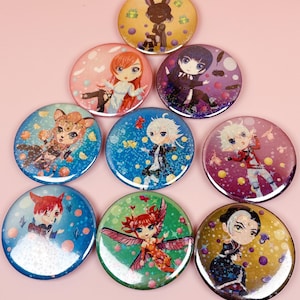 May include: A collection of nine colorful round pinback buttons. Each button features a different anime-style character illustration. The backgrounds vary in color, including pink, blue, green, and yellow, with decorative elements like stars and bubbles.