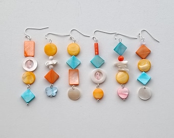 May include: Set of six colorful earrings with a geometric design. Each earring features a combination of blue, orange, white, and pink shell-like beads.