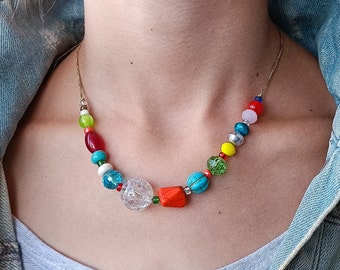May include: A colorful beaded necklace with red, orange, yellow, green, blue, and white beads. The necklace is made of various materials, including glass, plastic, and metal.