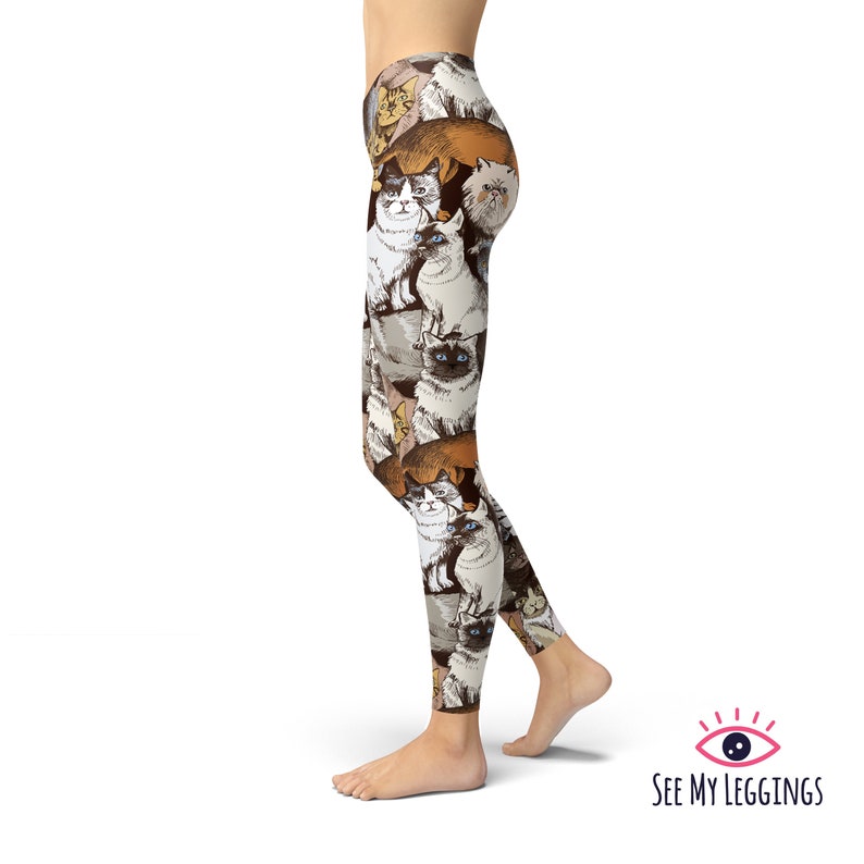 May include: A pair of leggings with a colorful pattern of cats. The leggings are white with brown, orange, and gray cats.