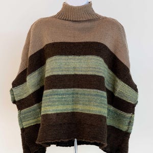 Puede incluir: Un jersey de cuello alto a rayas en tonos marrón, verde y beige. El jersey se exhibe en un maniquí blanco. El tejido de punto tiene cuello alto y mangas cortas. El texto "WOOL & Textures" es visible en la esquina inferior derecha.