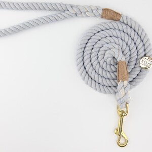 Pu&ograve; includere: Un guinzaglio per cani grigio chiaro realizzato in corda spessa e ritorta. Il guinzaglio &egrave; arrotolato e presenta inserti in tessuto beige e un moschettone e ferramenta in metallo color oro. L'impugnatura &egrave; ad anello per un facile trasporto.