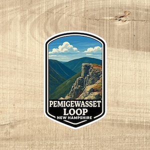 May include: A sticker featuring a scenic landscape with mountains, a blue sky, and white clouds. The sticker has a black border and text that reads "PEMIGEWASSET LOOP NEW HAMPSHIRE."