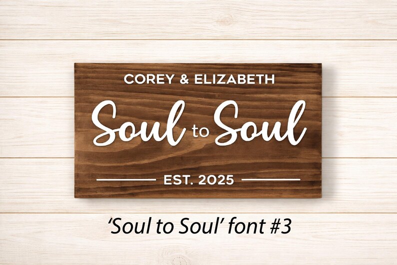 May include: A rectangular wooden sign with the words "COREY & ELIZABETH" above "Soul to Soul" in white script. Below, it reads "EST. 2025". The sign is a dark brown color. The text "'Soul to Soul' font #3" is below the sign.