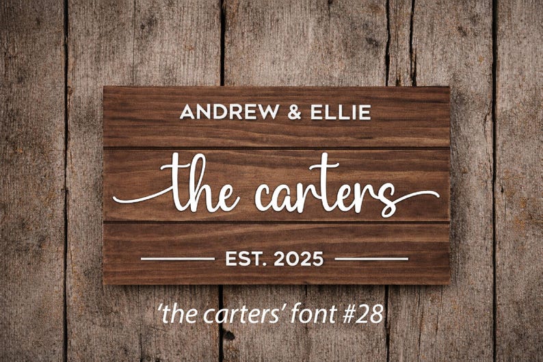 May include: A rectangular wooden sign with the names "Andrew & Ellie" above "the carters" in a cursive font. Below is "EST. 2025". The sign is brown with white lettering, set against a wooden background. The text "'the carters' font #28" is at the bottom.