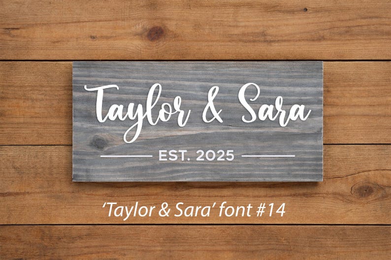 May include: A rectangular wooden sign with the names "Taylor & Sara" in white script, and "EST. 2025" below. The sign is gray and set against a wooden background. The text "'Taylor & Sara' font #14" is at the bottom.