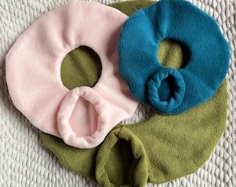 May include: Three fabric neck warmers in pink, teal, and olive green. Each warmer has a hole in the center for the neck.
