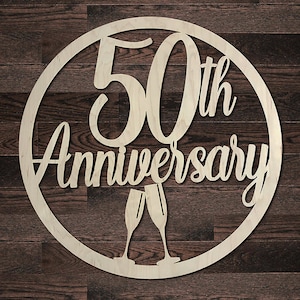 May include: A white wooden circular sign with the text "50th Anniversary" and two champagne glasses.