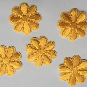May include: Five yellow felt flower patches with a daisy design. The flowers are approximately 2 inches in diameter.