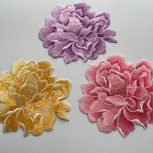 Pode incluir: Três remendos de flores bordadas em rosa, roxo e amarelo. As flores são todas peônias com pontos detalhados.