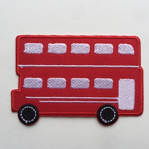 Puede incluir: Un parche bordado rojo con la forma de un autobús de dos pisos. El autobús tiene ventanas blancas, una puerta blanca y ruedas negras con costuras blancas. El parche es rectangular con esquinas redondeadas.