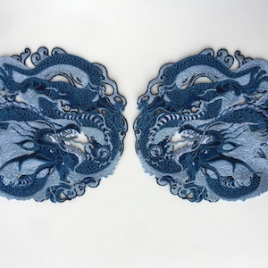 Könnte beinhalten: Zwei blaue gestickte Aufnäher mit einem Drachenmotiv. Die Aufnäher sind mit aufwendigen Nähten verziert und haben ein hellblaues und dunkelblaues Farbschema.