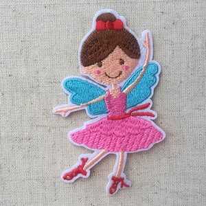 May include: Embroidered iron-on patch of a smiling fairy with brown hair, a pink dress, blue wings, and red shoes.