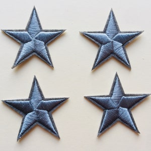 Könnte beinhalten: Vier silberfarbene, fünfzackige, sternförmige Stoff-Patches.