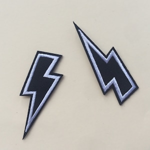 May include: Two black lightning bolt iron-on patches with white outlines.