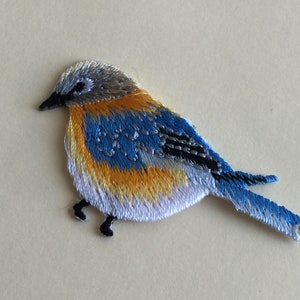 Könnte beinhalten: Gestickter Blaumeisen-Aufnäher mit weißen, gelben und schwarzen Akzenten. Der Vogel schaut nach rechts und hat einen langen Schwanz.