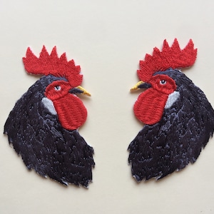 May include: Two black embroidered rooster patches with red combs and wattles. The roosters are facing each other.