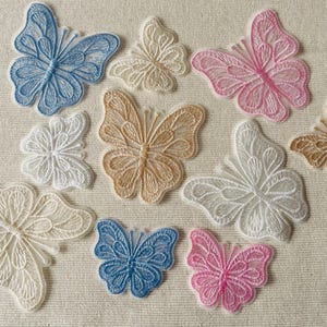 Puede incluir: Surtido de apliques de mariposa bordados en varios colores, incluyendo blanco, rosa, azul y beige. Los apliques están hechos de encaje delicado y presentan diseños intrincados.