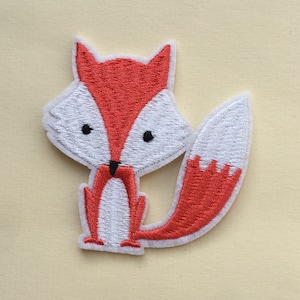 May include: A red and white embroidered iron-on patch of a cartoon fox. The fox has a white face with black eyes and a black nose. The fox is standing on all fours with its tail curled behind it.