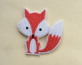 Op de afbeelding: Een rood en wit geborduurde strijk-op patch van een cartoon vos. De vos heeft een wit gezicht met zwarte ogen en een zwarte neus. De vos staat op alle vier poten met zijn staart gekruld erachter.