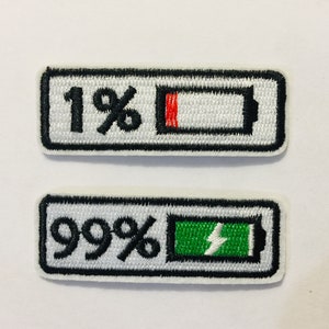 May include: Two embroidered iron-on patches depicting a battery icon with a percentage. The top patch shows a battery icon with 1% charge and a red bar. The bottom patch shows a battery icon with 99% charge and a green bar with a lightning bolt.