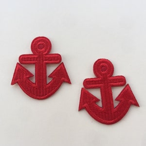 Puede incluir: Dos parches de ancla bordados en rojo. Cada parche presenta un diseño detallado de un ancla, con una barra vertical central, una barra transversal horizontal y uñas curvas. Los parches son probablemente para coser o planchar sobre tela.