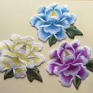 May include: Three embroidered fabric flower patches. One is blue, one is yellow, and one is purple.