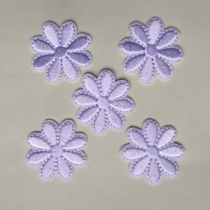 Könnte beinhalten: Fünf gestickte Blumenpatches in Lavendelfarbe. Jeder Patch zeigt ein einfaches Gänseblümchen-Design mit einem weißen Umriss.