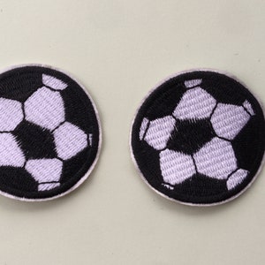 May include: Two black and white embroidered iron-on patches of a football.