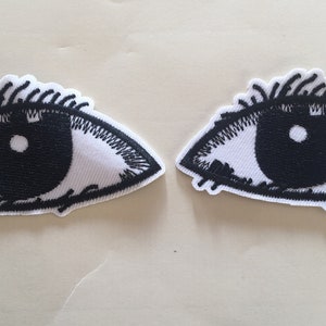 May include: Two black and white embroidered iron-on patches of eyes with eyelashes.