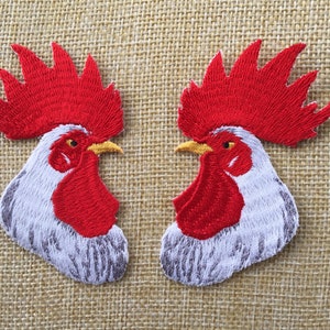 May include: Two embroidered iron-on patches of white roosters with red combs and wattles. The roosters are facing each other.