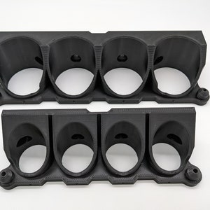 以下が含まれることがあります： 4つの穴がそれぞれ開いた黒いプラスチック製のゲージマウントが2つ。丸いゲージを保持するように設計されています。マウントは3Dプリントされたプラスチック製で、表面にテクスチャがあります。