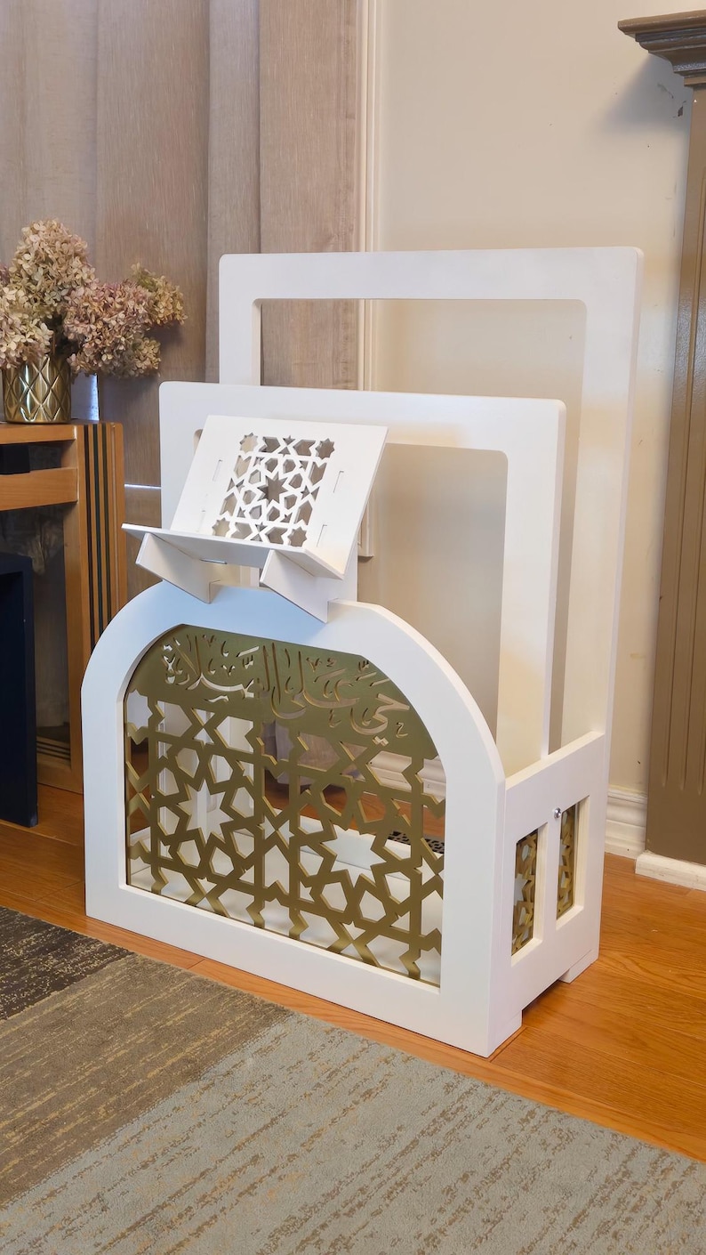 Op de afbeelding: Een witte houten boekenstandaard met een gouden boog met patroon en een kleinere witte standaard erboven. De standaard is ontworpen om boeken en andere items te houden.