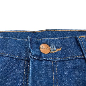 K&ouml;nnte beinhalten: Nahaufnahme einer blauen Jeans mit einem kupferfarbenen Knopf. Der Knopf ist mit dem Markennamen "Wrangler" gepr&auml;gt. Die Jeans hat gelbe N&auml;hte und ein klassisches Design.