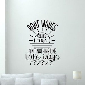 May include: Black and white text on a white background that reads "Boat Waves Sun Rays Ain't Nothing Like Lake Days" with a stylized sun and waves underneath the text.