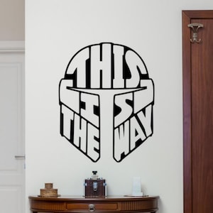 Könnte beinhalten: Schwarz-weiße Wanddekoration mit einem Mandalorianer-Helm, in den die Worte "This is the way" integriert sind.