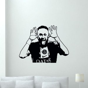 May include: Black and white silhouette of a soccer player sticking out his tongue and making a silly face. The player is wearing a jersey with the text "QATAR" and a soccer team logo.