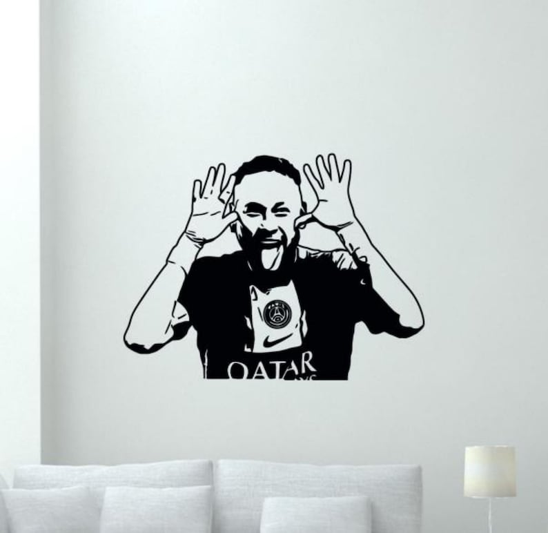 May include: Black and white silhouette of a soccer player sticking out his tongue and making a silly face. The player is wearing a jersey with the text "QATAR" and a soccer team logo.