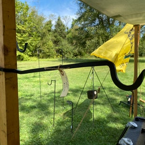 May include: A black metal hook attached to a wooden post. The hook is curved and has a small tag attached to it that says "Handmade in the USA".