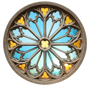 May include: Circular stained glass window with a stone frame. The design features a symmetrical pattern of blue, yellow, and clear glass segments. The stone frame has a textured, weathered appearance, and the glass is set against a bright background.