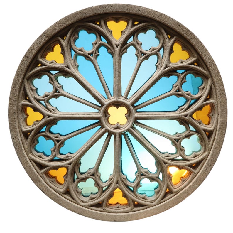 May include: Circular stained glass window with a stone frame. The design features a symmetrical pattern of blue, yellow, and clear glass segments. The stone frame has a textured, weathered appearance, and the glass is set against a bright background.