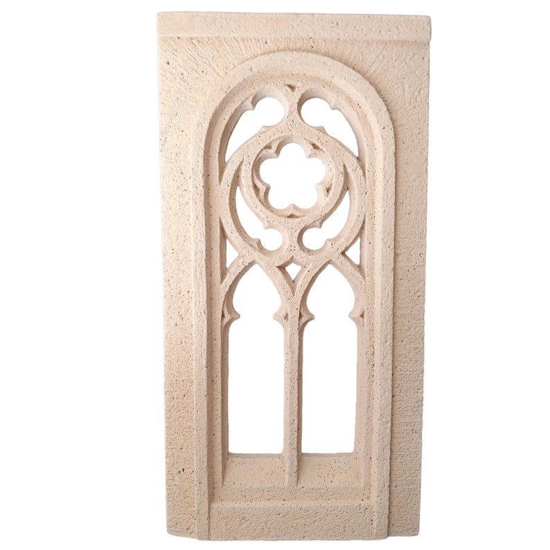 May include: A beige stone wall decor with a carved arched window design. The window has a detailed pattern of circles and arches.