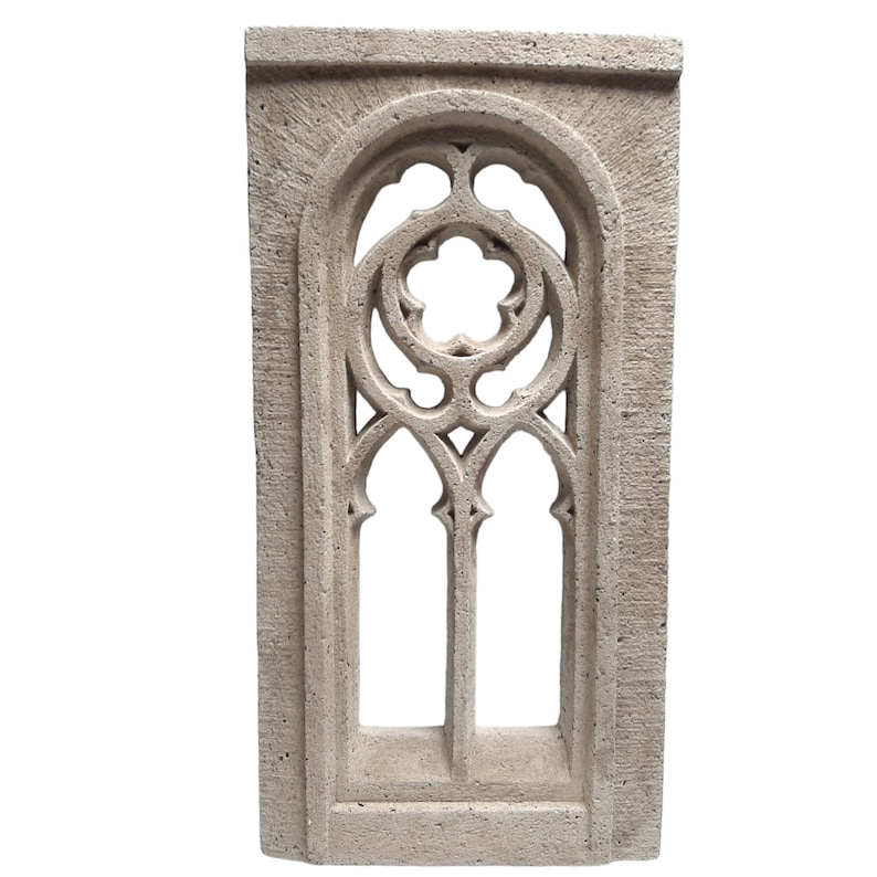 May include: A decorative stone window frame with a detailed gothic arch design. The frame is made of a light beige stone and has a rough texture.
